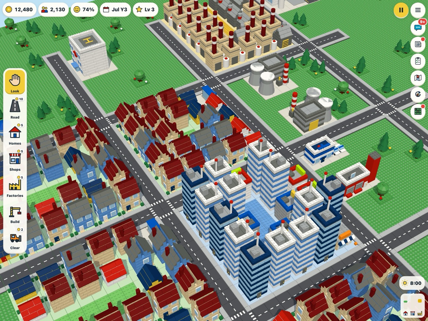A Brick City town: brick houses with red roofs, blue and white tower blocks and factories on a green baseplate.